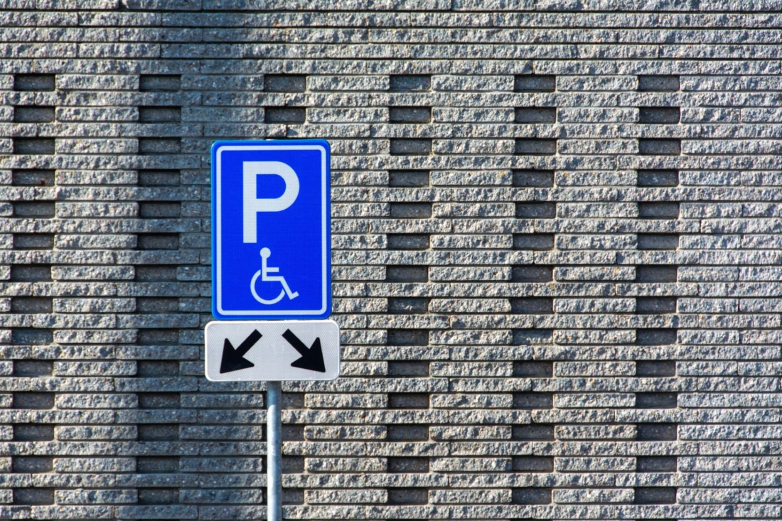 Miejsce parkingowe dla osób niepełnosprawnych oznaczone niebieskimi i białymi symbolami.